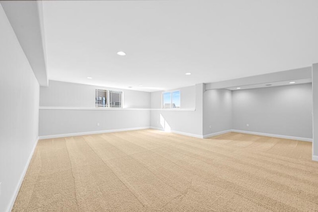 below grade area featuring light carpet, recessed lighting, and baseboards