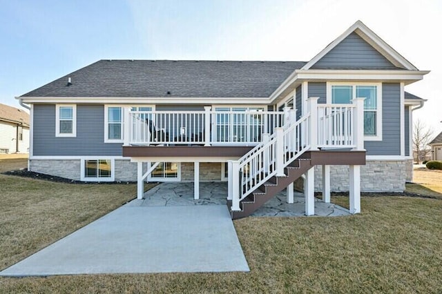 rear view of property with a yard, roof with shingles, a deck, and stairs