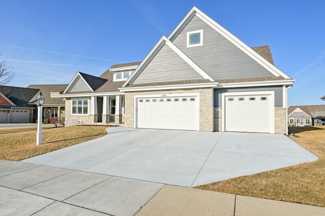 craftsman-style home with an attached garage, concrete driveway, and a front yard