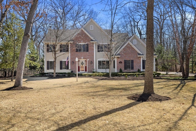 colonial-style house featuring brick siding and a front lawn