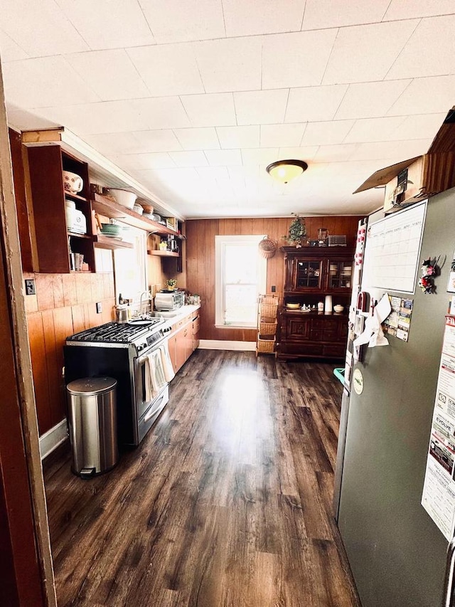 kitchen featuring open shelves, dark wood-style floors, stainless steel appliances, wooden walls, and baseboards