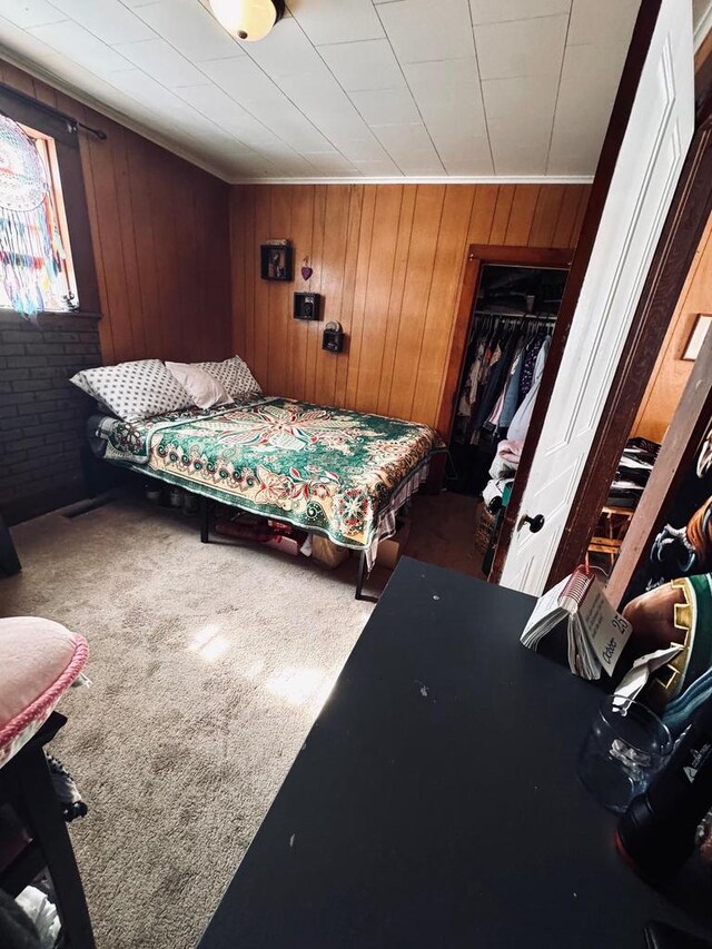 carpeted bedroom featuring a closet, wood walls, and brick wall