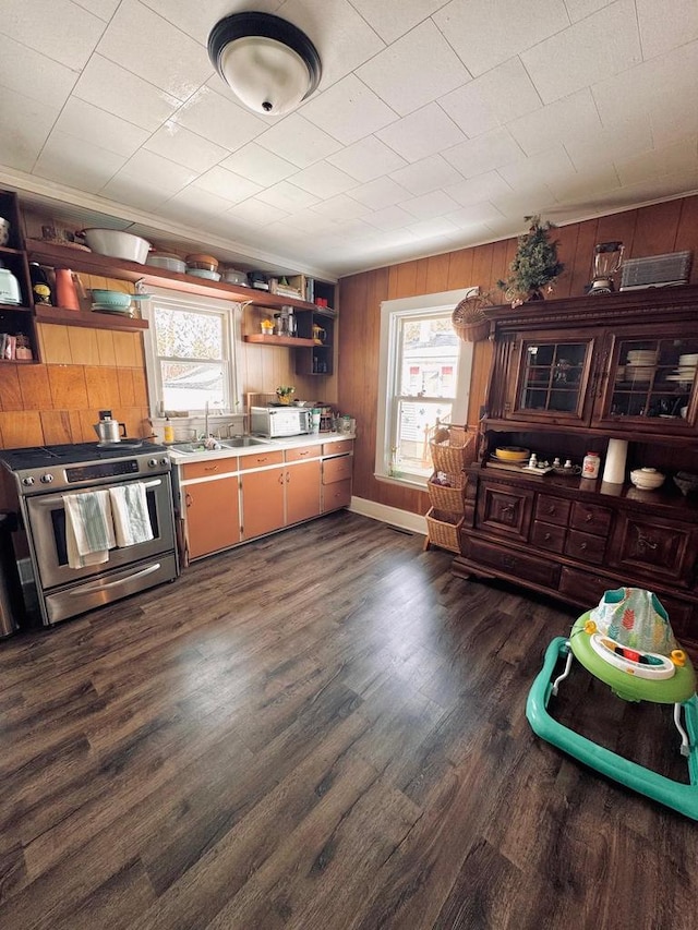 kitchen featuring open shelves, dark wood-type flooring, light countertops, stainless steel gas stove, and a sink