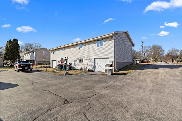 rear view of property featuring driveway and a garage