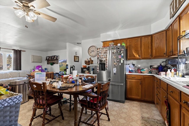 kitchen with open floor plan, stainless steel fridge with ice dispenser, brown cabinets, and light floors