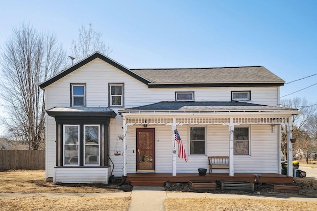 view of front of house with a porch, a shingled roof, and fence