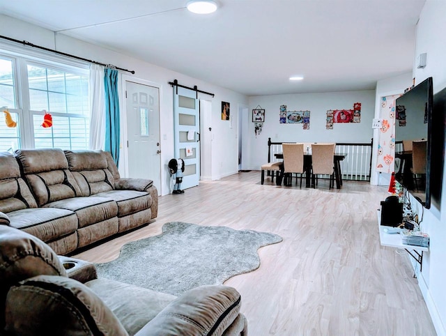 living room with a barn door, baseboards, and wood finished floors