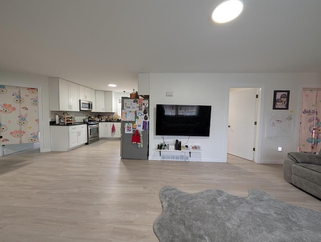 living room featuring light wood-style floors, visible vents, and baseboards