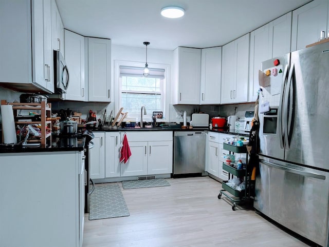 kitchen with dark countertops, white cabinets, appliances with stainless steel finishes, and a sink