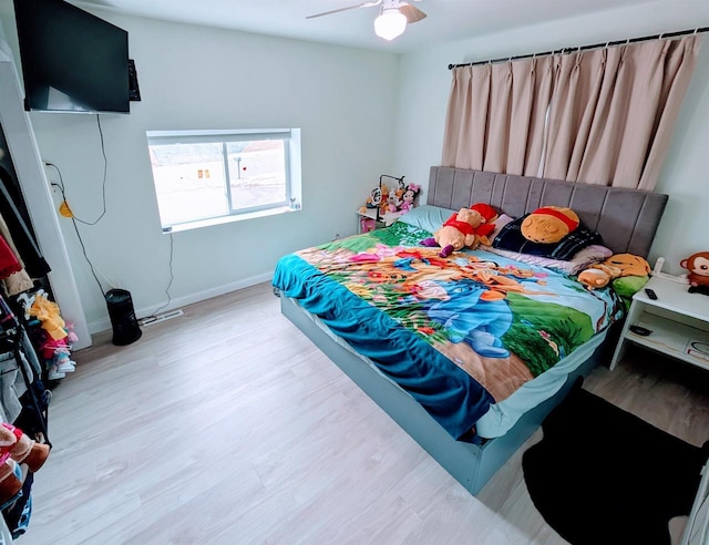 bedroom with a ceiling fan, wood finished floors, and baseboards