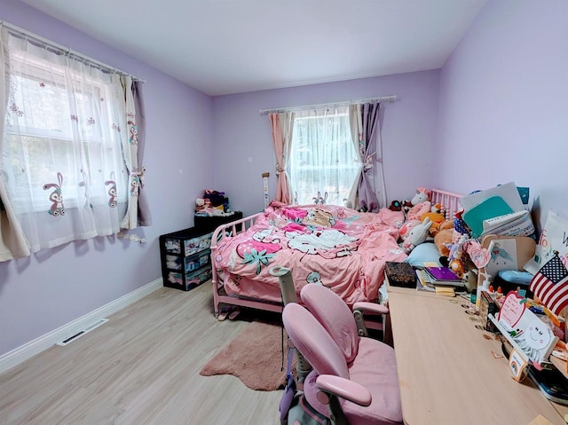 bedroom with visible vents, baseboards, and wood finished floors