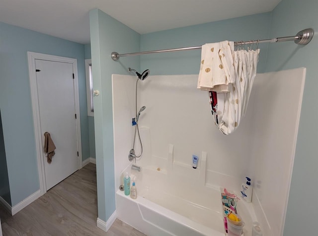 bathroom featuring bathtub / shower combination, wood finished floors, and baseboards