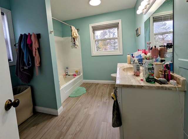 bathroom with a wealth of natural light, vanity, baseboards, and wood finished floors