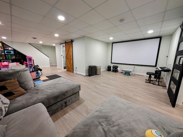 cinema room featuring baseboards, a drop ceiling, a barn door, recessed lighting, and wood finished floors