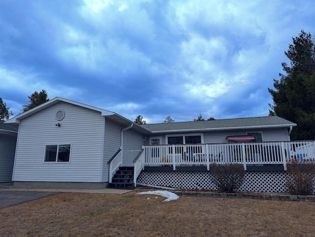 rear view of house featuring a wooden deck and a yard