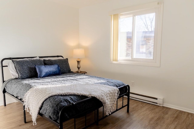 bedroom featuring wood finished floors, baseboards, and a baseboard radiator