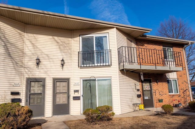 townhome / multi-family property with a balcony and brick siding