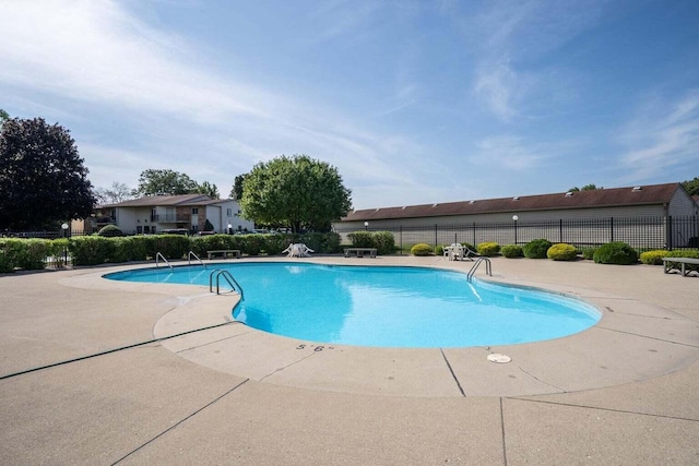 community pool with a patio area and fence