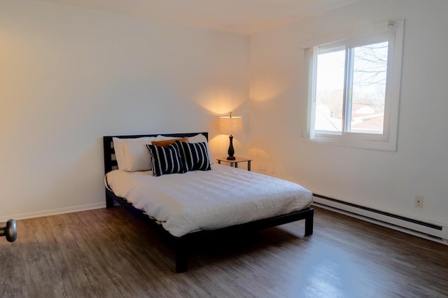 bedroom featuring a baseboard heating unit, wood finished floors, and baseboards