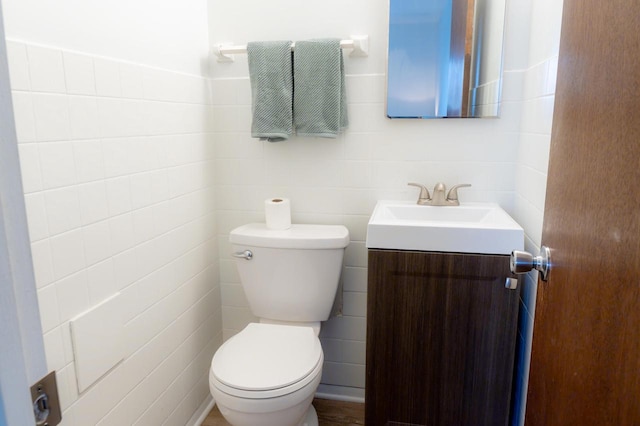 half bath with vanity, tile walls, and toilet