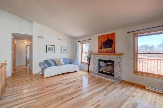 living area with a glass covered fireplace, visible vents, and wood finished floors