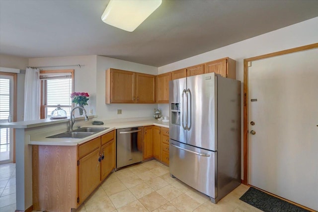 kitchen with light tile patterned floors, a peninsula, a sink, light countertops, and appliances with stainless steel finishes