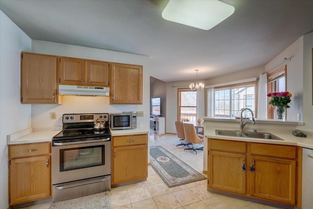 kitchen with under cabinet range hood, light countertops, appliances with stainless steel finishes, and a sink