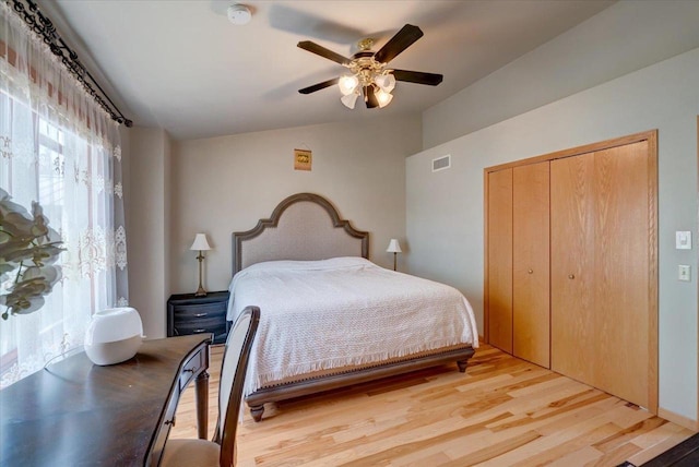 bedroom with a ceiling fan, visible vents, lofted ceiling, a closet, and light wood-type flooring