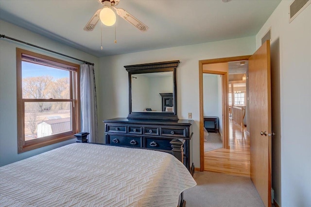 bedroom featuring visible vents, multiple windows, light colored carpet, and ceiling fan