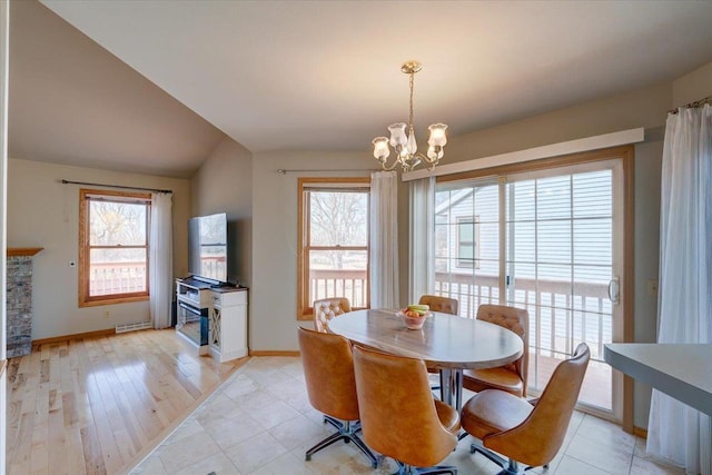 dining space featuring an inviting chandelier, lofted ceiling, plenty of natural light, and a stone fireplace