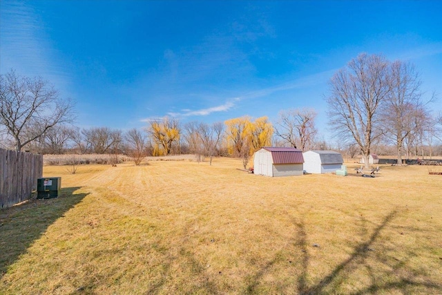 view of yard with an outbuilding, a rural view, a storage unit, and fence