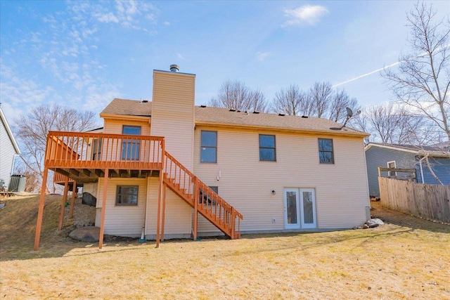 rear view of property featuring stairway, fence, a chimney, a deck, and a lawn