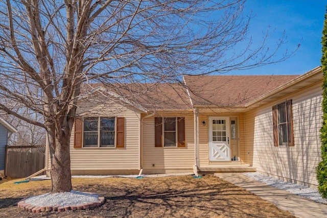 ranch-style house with a shingled roof and fence