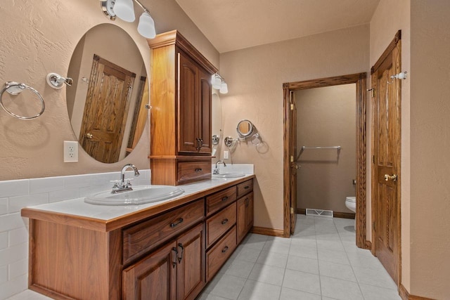 bathroom featuring double vanity, tile patterned floors, toilet, and a sink