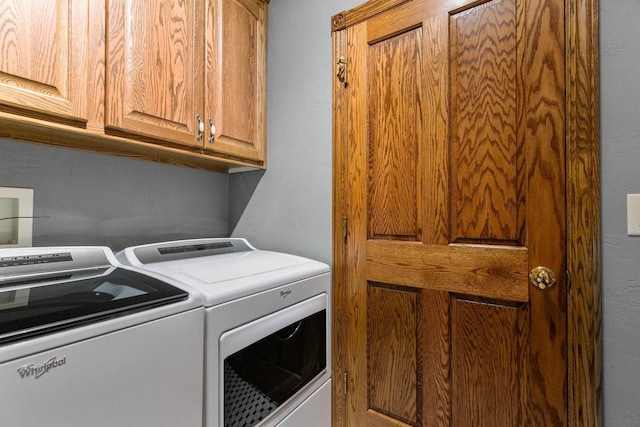 clothes washing area featuring washer and clothes dryer and cabinet space