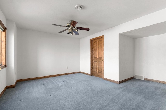 carpeted spare room with visible vents, baseboards, and a ceiling fan