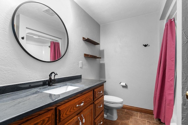 full bath featuring visible vents, baseboards, toilet, a textured wall, and vanity