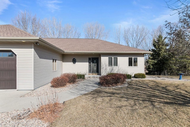 ranch-style home with an attached garage, a shingled roof, and a front yard