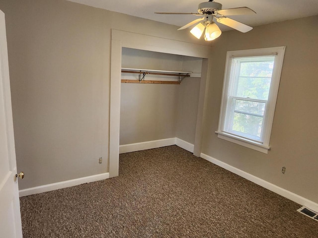 unfurnished bedroom featuring visible vents, baseboards, dark colored carpet, and a closet