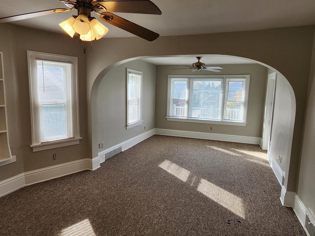 unfurnished room with a ceiling fan, baseboards, visible vents, and dark carpet