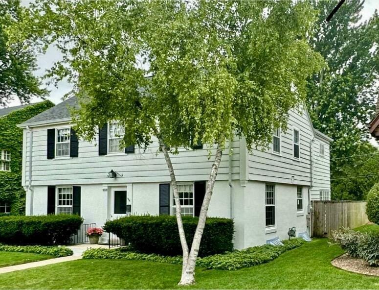 view of front of property featuring a front lawn, fence, and stucco siding