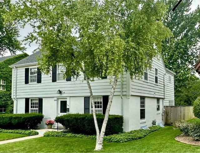 view of front of property featuring a front lawn, fence, and stucco siding