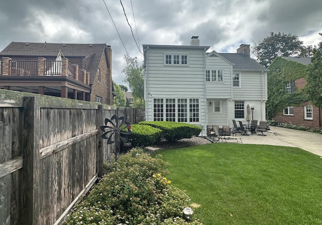 back of property with a patio, a lawn, fence, and a chimney