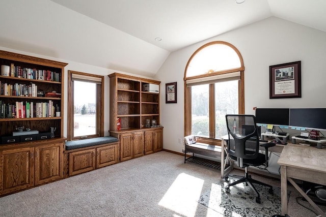 office featuring lofted ceiling, a healthy amount of sunlight, and light carpet