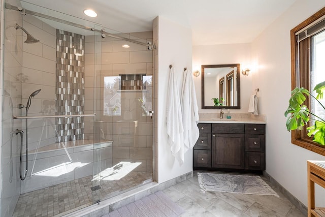 bathroom with a stall shower, vanity, and baseboards