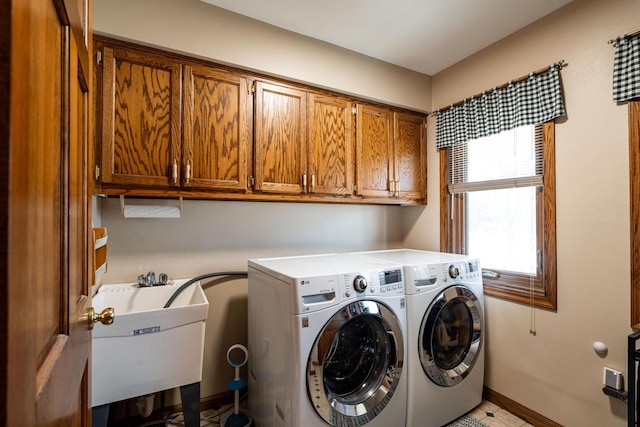 washroom featuring washing machine and dryer, cabinet space, baseboards, and a sink