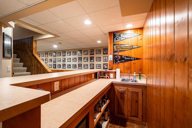 bar featuring stairway, recessed lighting, a drop ceiling, a sink, and indoor wet bar