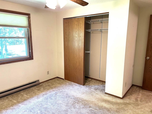 unfurnished bedroom featuring baseboards, a baseboard radiator, light carpet, and a closet