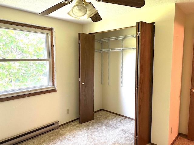 unfurnished bedroom featuring a baseboard heating unit, multiple windows, a closet, and light carpet