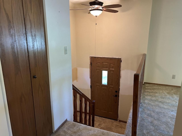 carpeted foyer entrance with a ceiling fan and baseboards